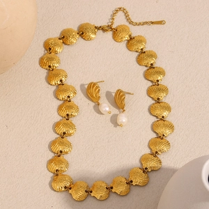 Détail du collier coquillage doré 18K et boucles d'oreilles perles sur fond beige