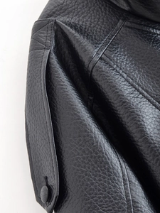 Vue macro de la texture cuir grainé et des coutures sur une veste noire pour femmes