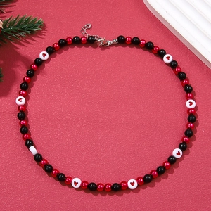 Detailed view of Christmas pearl necklace with red heart beads on festive background