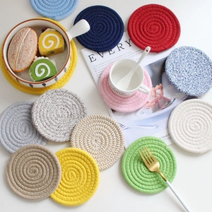 Set of colorful round woven cotton coasters in various colors on a white table