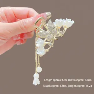 Détail d'une pince à cheveux tulipe dorée avec papillon et pampilles de perles