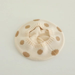 Detail of soft cream knitted beret with brown polka dots showing warm yarn texture