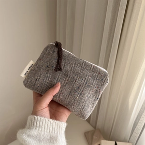 Macro detail of grey herringbone tweed mini pouch with zipper and simple wish label