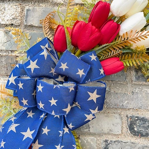 Patriotischer Kranz mit roten und weißen Tulpen und blauer Sternschleife an Ziegelwand