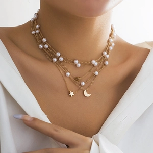 Layered gold necklace with white pearls featuring star and moon charms on model
