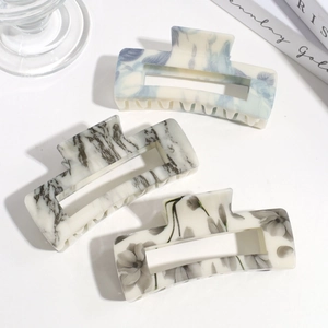 Three rectangular acetate hair claws with blue, black, and grey marble patterns on white