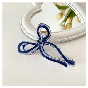 Detail of 11cm blue bow hair claw clip made of acrylic on a stylish desk background