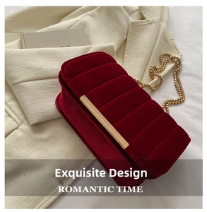 Close-up of red velvet chain bag with golden metal buckle on tweed background