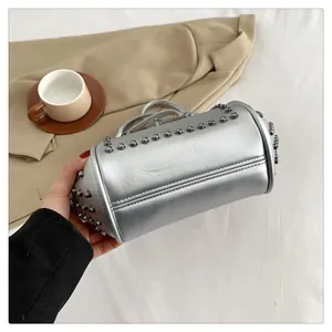 Close-up of silver metallic shell bag with round rivets and a stylish chain strap