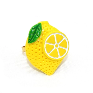 Close-up of lemon napkin ring with yellow fruit and green leaf on white fabric