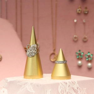 Golden cone jewelry display stands with swan diamond ring on elegant green velvet