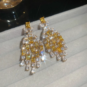 Detailed macro of luxury gold tassel earrings with yellow zircons in a gray jewelry box