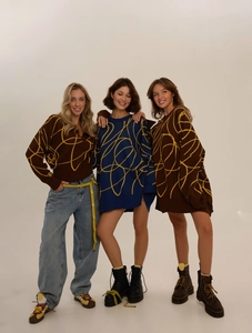 Detail of oversized knit sweater featuring abstract yellow graffiti lines on brown and blue