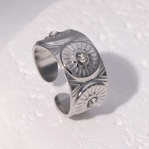 Bague ouverte argentée avec relief solaire et cristaux sur fond blanc texturé