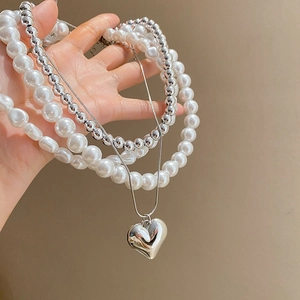 Détail du collier de perles superposées avec pendentif en forme de cœur poli