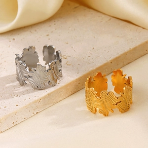 Adjustable leaf open rings in gold and silver finish on a textured stone surface