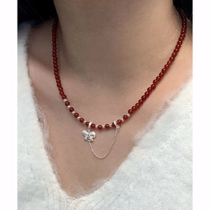 Close-up of red beaded necklace with silver butterfly pendant worn on a model