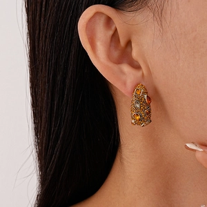 Detailed close-up of vintage gold earrings with amber gems and orange diamonds on model