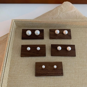 Set of minimalist vintage pearl stud earrings in various sizes on dark wooden cards