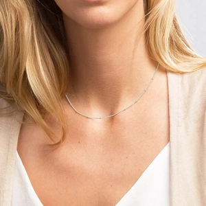 Close-up of minimalist silver ball chain necklace worn on a female model's neck