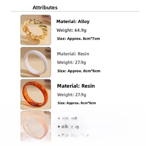 Detail of twisted gold metal cuff and resin bracelets with amber and white finishes
