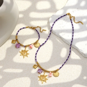 Détail du collier et bracelet en corde tressée avec pendentifs dorés et fleurs