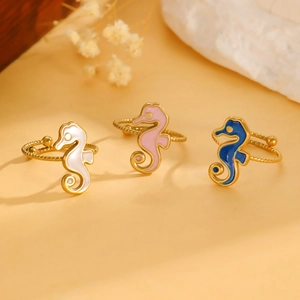 Detailed view of three seahorse rings in white, pink, and blue enamel with gold rope bands