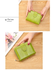Detail of a grass green soft leather wallet with zip closure and metallic buckle