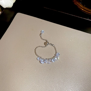 Detail of adjustable silver ring with sparkling round zircon row on beige texture