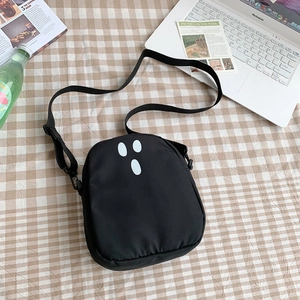 Détail du sac bandoulière noir en toile avec motif fantôme sur un bureau décoré