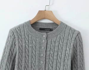 Macro detail of grey cable knit cardigan featuring round neck and classic textures