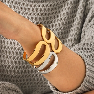 Three stacked wavy stainless steel open bangles in gold and silver finish on model