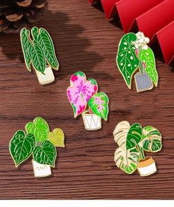 Detailed display of five enamel potted plant brooches on dark wood texture background