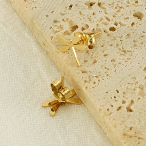 Minimalist 14k gold dragonfly stud earrings in stainless steel on a textured stone base