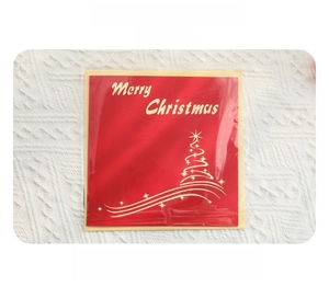 Flat lay of red Christmas card with gold tree design, envelope, and clear OPP bag