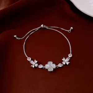 Silver flower bracelet with cat eye stone and clover pendant on red velvet background
