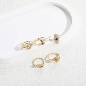 Five-piece gold ring set featuring evil eye, snake, and moon designs with blue stones