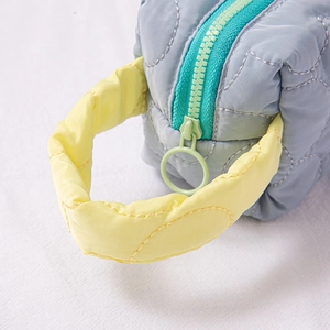 Close-up of light blue quilted fabric cosmetic bag with yellow handle and green zipper