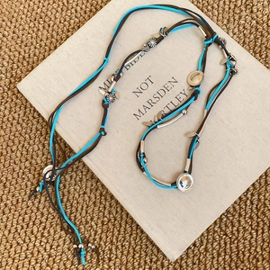 Detailed view of bohemian turquoise suede cord necklace with silver sunflower charms