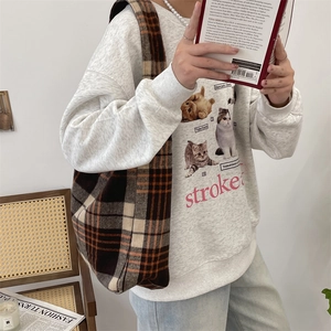 Detail of a large plaid tote bag paired with a gray sweatshirt in a cozy lifestyle setting