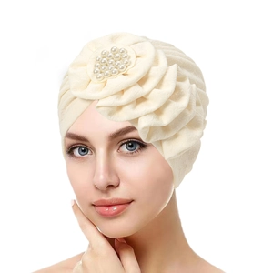 Close-up of beige pleated headscarf featuring large fabric flower and pearl accents