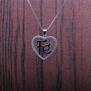 Detailed close-up of heart-shaped FE necklace with zircon inlay on a dark wooden surface