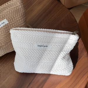 Close-up of textured woven fabric cosmetic bags with simple wish label on wooden table