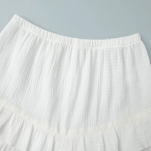 Dettaglio di pantaloncini in mussola di cotone bianco con vita elastica e pizzo delicato
