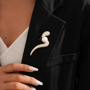 Detail of 14k gold plated S-shape brooch with pearls and zircon on a black blazer