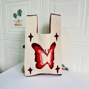 Close-up of butterfly knit pattern on cream tote bag with detailed red embroidery texture