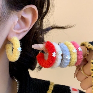 Close-up of soft flocked hoop earrings with silver snowflake pendants in various colors