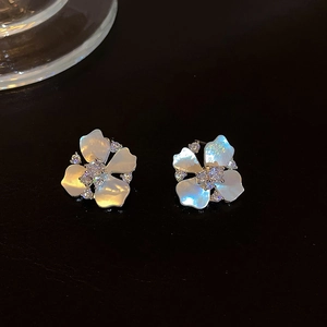 Macro shot of shell petal flower earrings with zircon on reflective black background