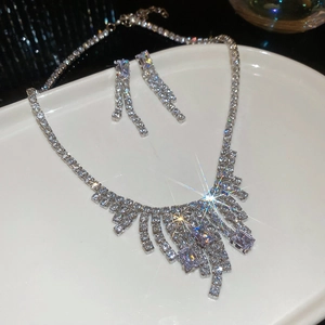 Detail of square zircon tassel necklace and earrings set on white tray with sparkling effect
