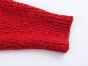 Detailed macro view of the red chunky knit sweater sleeve showing ribbed cuff texture